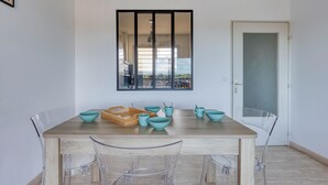 Un espace repas avec une table en bois, des chaises transparentes et des bols de couleur turquoise.