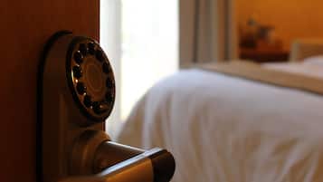 Une chambre d’hôtel avec une porte en bois, un trou de serrure et un lit recouvert de draps blancs.