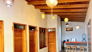 Corredor com portas de madeira, cozinha com banquetas e iluminação pendente.