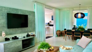 Una sala de estar moderna con un televisor de pantalla plana, un sofá, una mesa de centro y un comedor con sillas y una mesa.