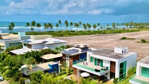 Una propiedad costera con edificios modernos, una playa y palmeras.