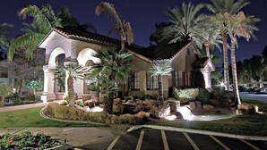 A building with a tiled roof, arched windows, and palm trees in the foreground. - Charming 3-bedroom condo with fitness room and WiFi in Scottsdale (Scottsdale)