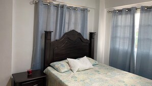 A bedroom with a wooden bed, a bedside table, and a wall-mounted air conditioner.