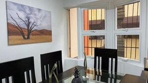 A dining area with a glass table, black chairs, and a painting of a desert landscape.