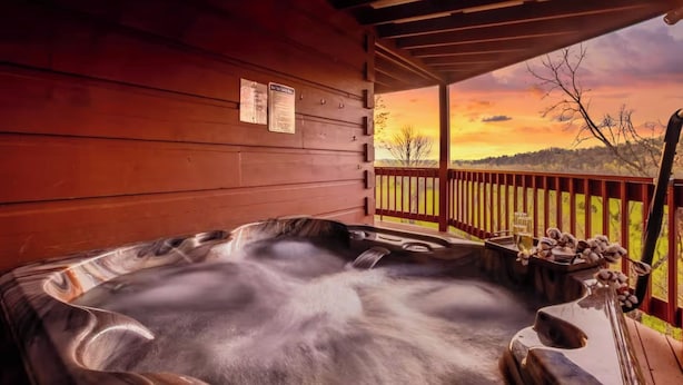 Un jacuzzi en una cabaña de madera con vista a un atardecer.