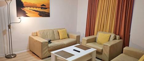 A living room with two beige sofas, a white coffee table, and a floor lamp.