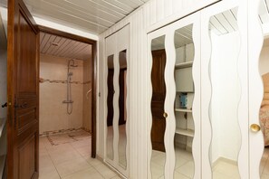 A room with a shower, wooden wardrobe, and a white door with a unique design. - 'Le Repaire' Apartment with Mountain View, Shared Terrace and Garden (Cassis)