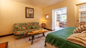 A room with a floral sofa, a small table, a bed with a green bedspread, and a framed picture on the wall. - Apartment 'Le Repaire' with Mountain View, Shared Terrace and Garden (Cassis)