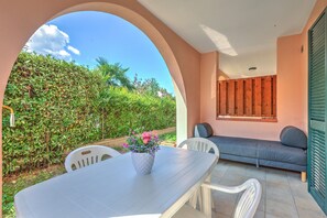 Un espacio al aire libre con mesas y sillas, un sofá y vistas a zonas verdes.