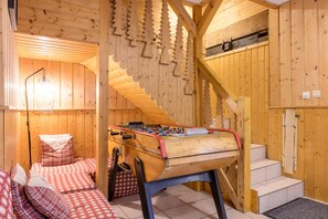 A cozy room with a foosball table, a bed with checkered bedding, and a wooden staircase.