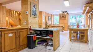 A wooden interior with a kitchen area, dining table, and chairs. - Apartment 'Des Sapins' with Mountain View, Private Terrace and Wi-Fi (La Bresse, Grand Est, France)