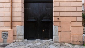 A double door with a fan above, set in a beige brick wall. - Apartment 'Melo' with Balcony, Wi-Fi and Air Conditioning (Palermo)
