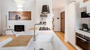 A modern kitchen with a white sink, stainless steel faucet, and a black hanging light fixture. - Apartment 'Melo' with Balcony, Wi-Fi and Air Conditioning (Palermo)
