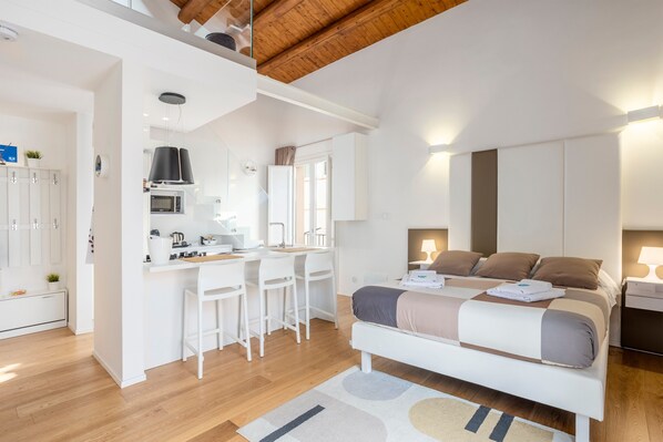 Une chambre moderne comprenant un lit, des tables de chevet et un espace bureau avec des chaises.