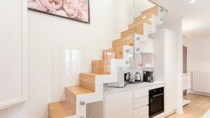 Eine moderne Küche mit weißen Schränken, einem eingebauten Backofen und einer Kaffeemaschine auf der Arbeitsplatte.