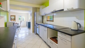 A modern kitchen with white cabinets, a black countertop, and a kettle.