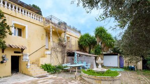 A courtyard with a fountain, outdoor seating, and a building with a balcony.