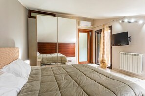 A bedroom with a large bed, a wardrobe, a television, and a radiator.