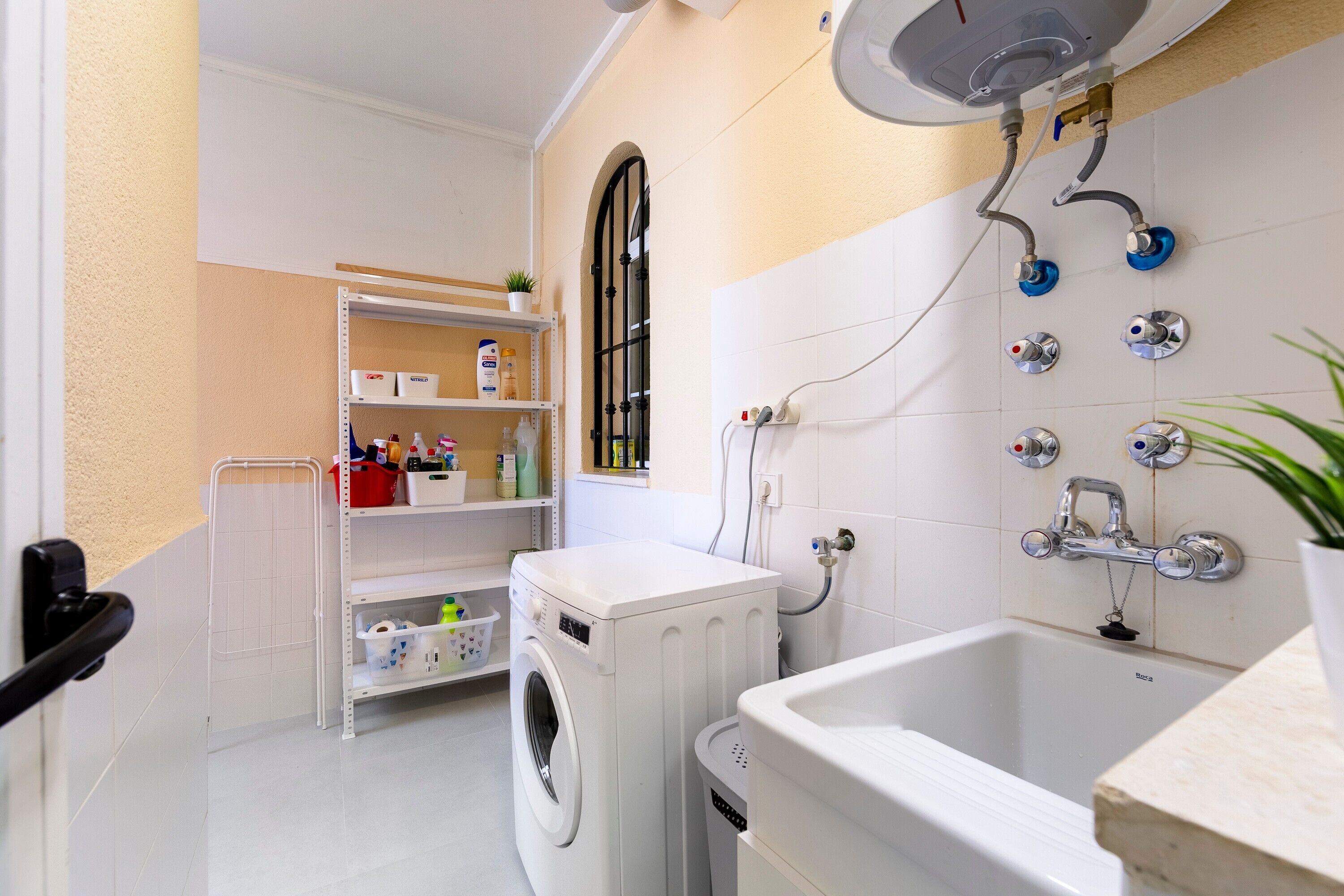 A laundry room with a washing machine, a sink, and a shower.