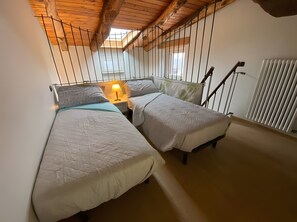 Ein Zimmer mit zwei Betten, einem Oberlicht, einer Heizung und einer Holzbalkendecke.