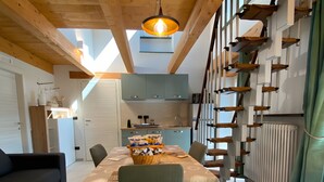 A dining area with a table set for two, a basket of snacks, and a modern kitchen in the background. - Holiday Home 'Alpi Liguri' with Mountain View, Shared Terrace and Wi-Fi (Peveragno)