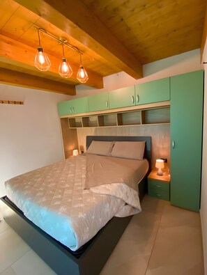 A bedroom with a bed, green cabinets, a nightstand, and pendant lighting. - Holiday Home 'Alpi Liguri' with Mountain View, Shared Terrace and Wi-Fi (Peveragno)