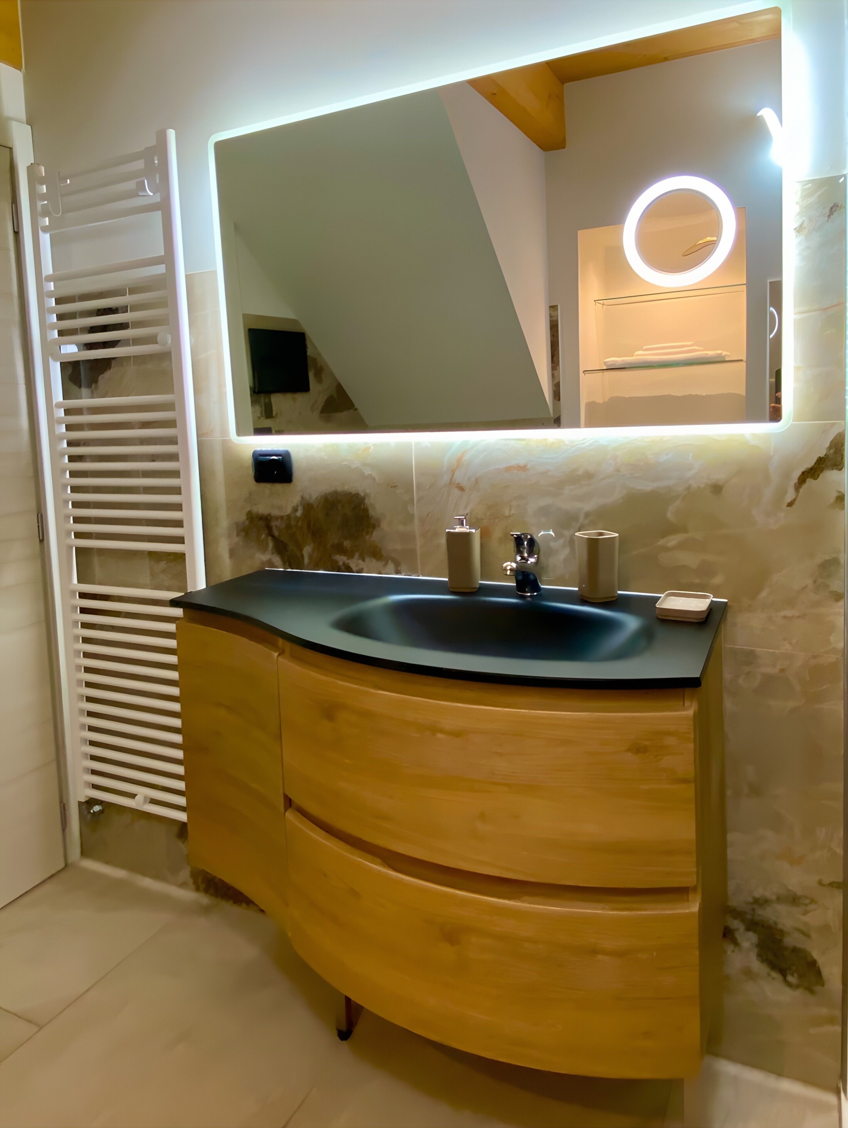 Une salle de bain avec un meuble-lavabo en bois aux lignes courbes, un lavabo avec un miroir et un porte-serviettes.