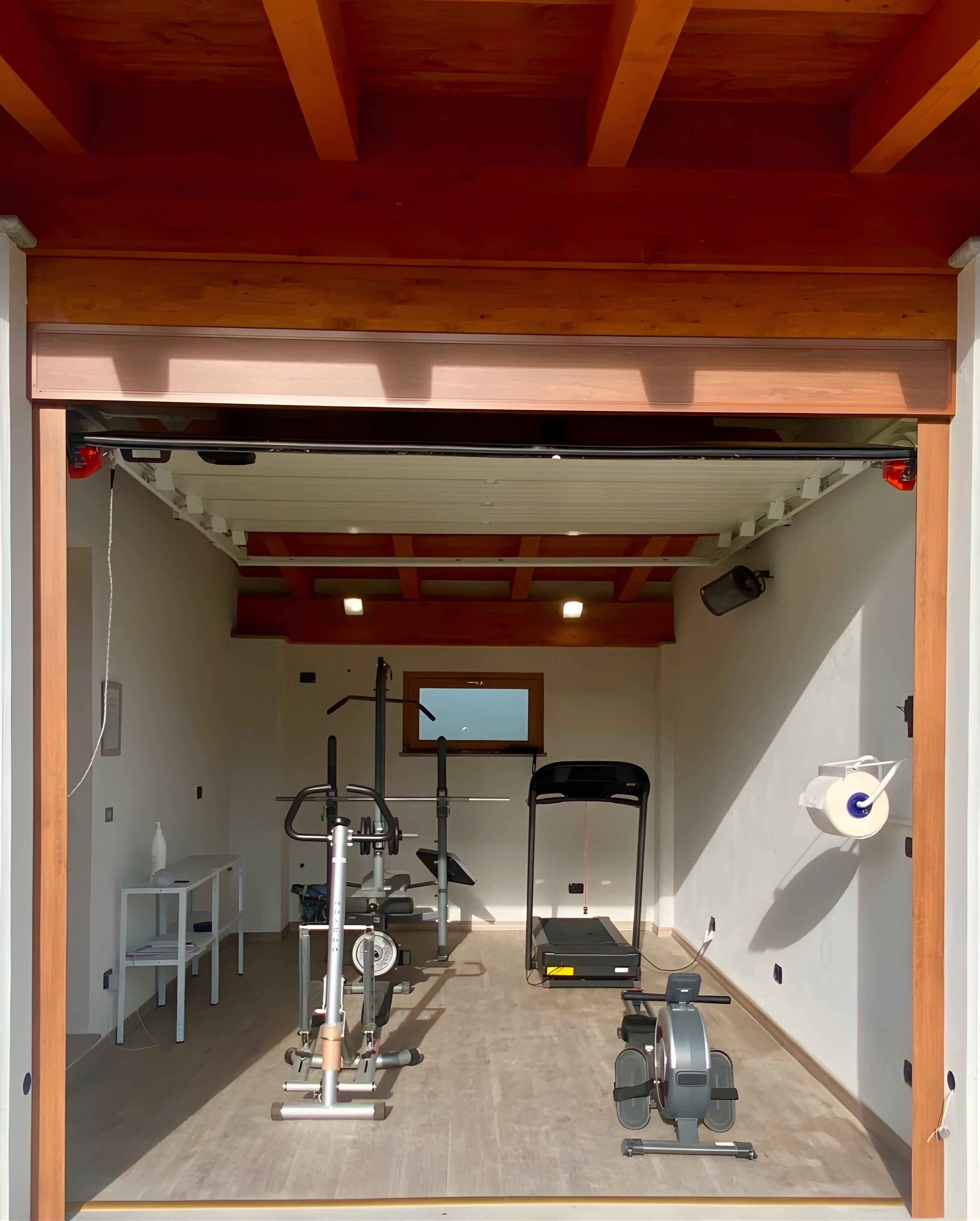 Ein Fitnessraum mit Trainingsgeräten, Laufband und Klimmzugstange.