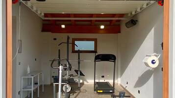 Ein Fitnessraum mit Trainingsgeräten, Laufband und Klimmzugstange.