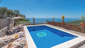 A rectangular pool with a decorative tile pattern, surrounded by a stone deck and a wooden fence. - Villa Vistas Nerja by Ruralidays (Málaga)