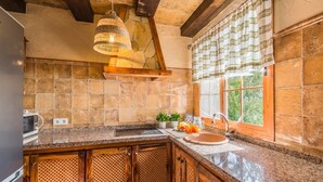 A kitchen with granite countertops, a built-in oven, and a window with curtains. - Villa Vistas Nerja by Ruralidays (Málaga)