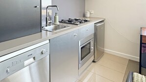 A modern kitchen with stainless steel appliances, a dishwasher, and a built-in oven. - Pret-A-Porter (Prahran)