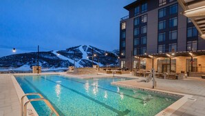 Une piscine à l’eau claire, un poste de surveillance pour les sauveteurs et une vue sur les montagnes en arrière-plan.