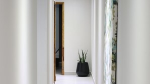 Ein moderner Flur mit einem Blumentopf, einer Tür am Ende und einer Wand mit floralem Muster.