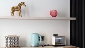 Eine moderne Küche mit einer Holzarbeitsplatte, einem Wasserkocher, einem Toaster und einer dekorativen Zebraschmuckfigur.