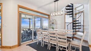 A dining area with a table and chairs, a staircase, and a view through a glass door. - Private Beach, Hot Tub w/ Ocean Views, Modern 4BR (Bethany Beach)