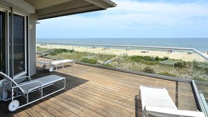 A wooden deck with lounge chairs and a glass door leading to a beach view. - Private Beach, Hot Tub w/ Ocean Views, Modern 4BR (Bethany Beach)