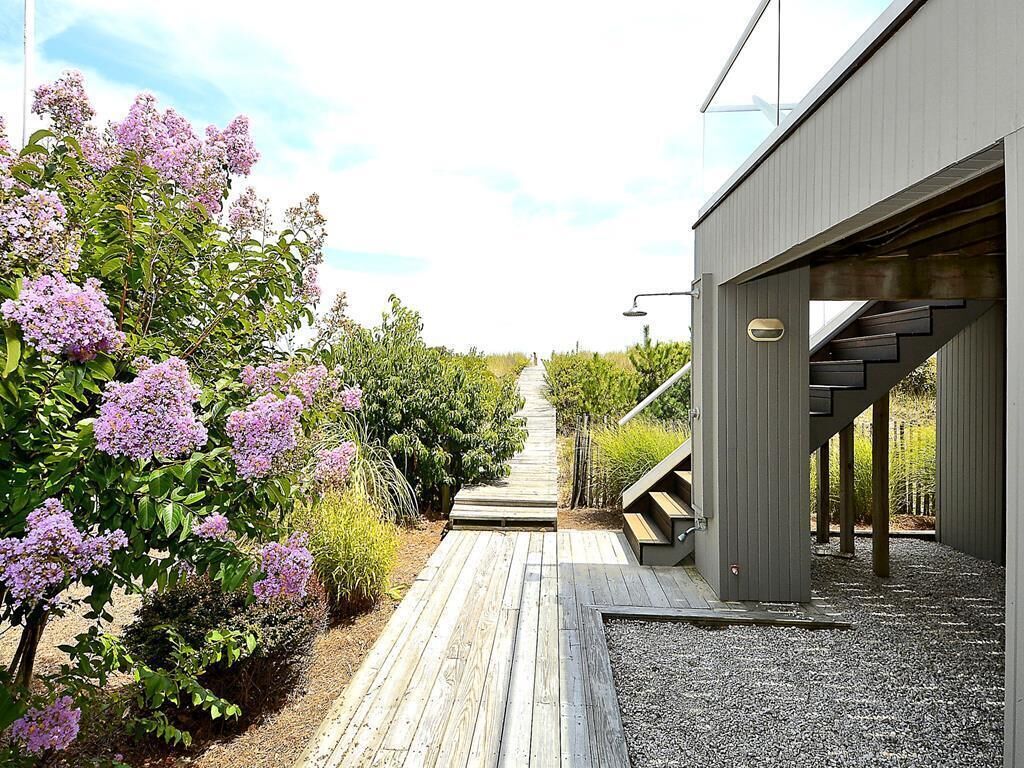 A modern building with a wooden deck and a pathway leading to a covered entrance.