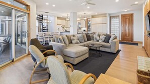 A spacious living area with a sectional sofa, a dining table, and a kitchen in the background. - Private Beach, Hot Tub w/ Ocean Views, Modern 4BR (Bethany Beach)