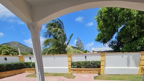 Ein überdachter Patio-Bereich mit Fliesenboden, einem kleinen Tisch und Stühlen.
