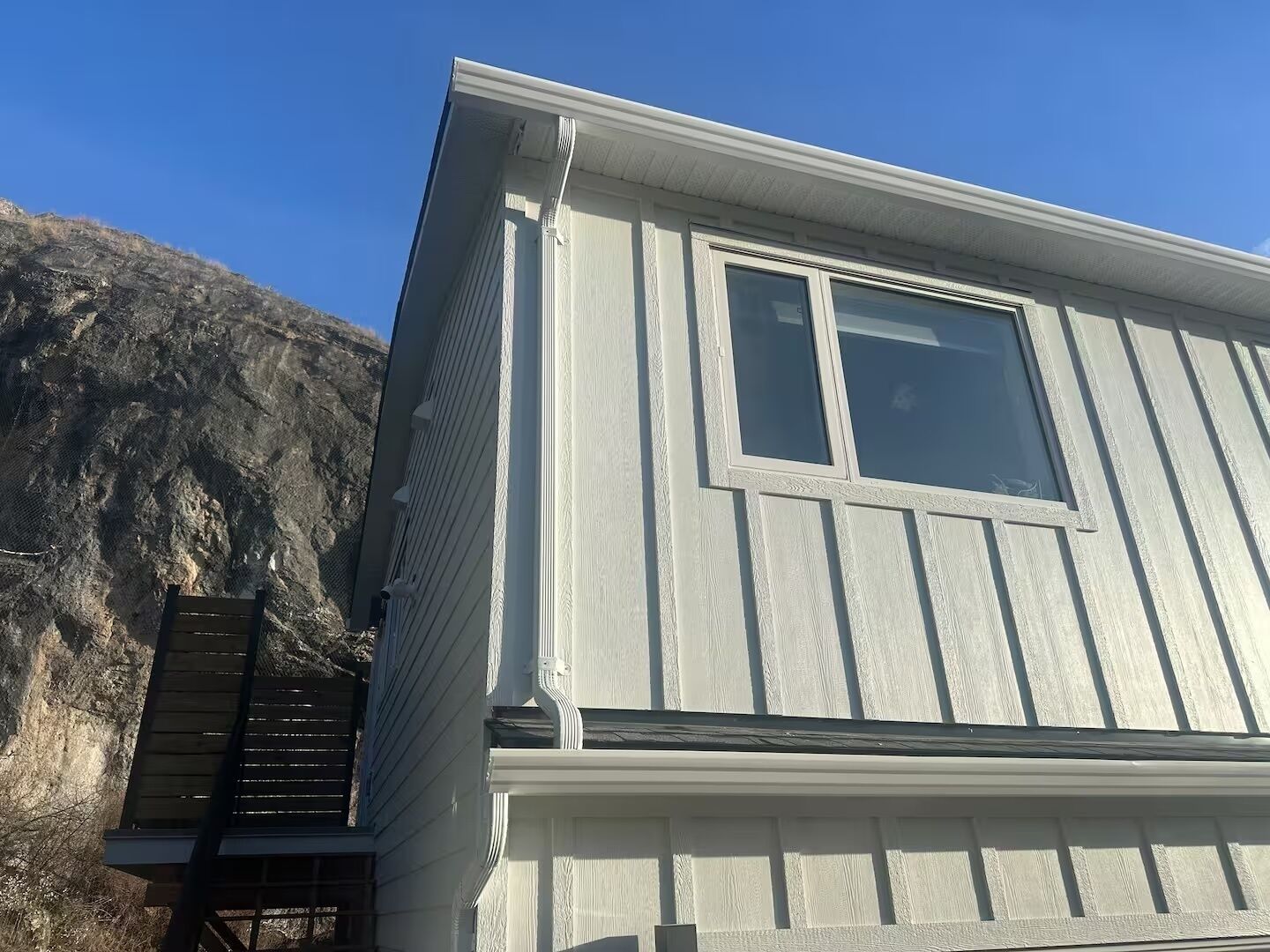 Un bâtiment à deux étages doté d’une grande fenêtre et d’une terrasse en bois.