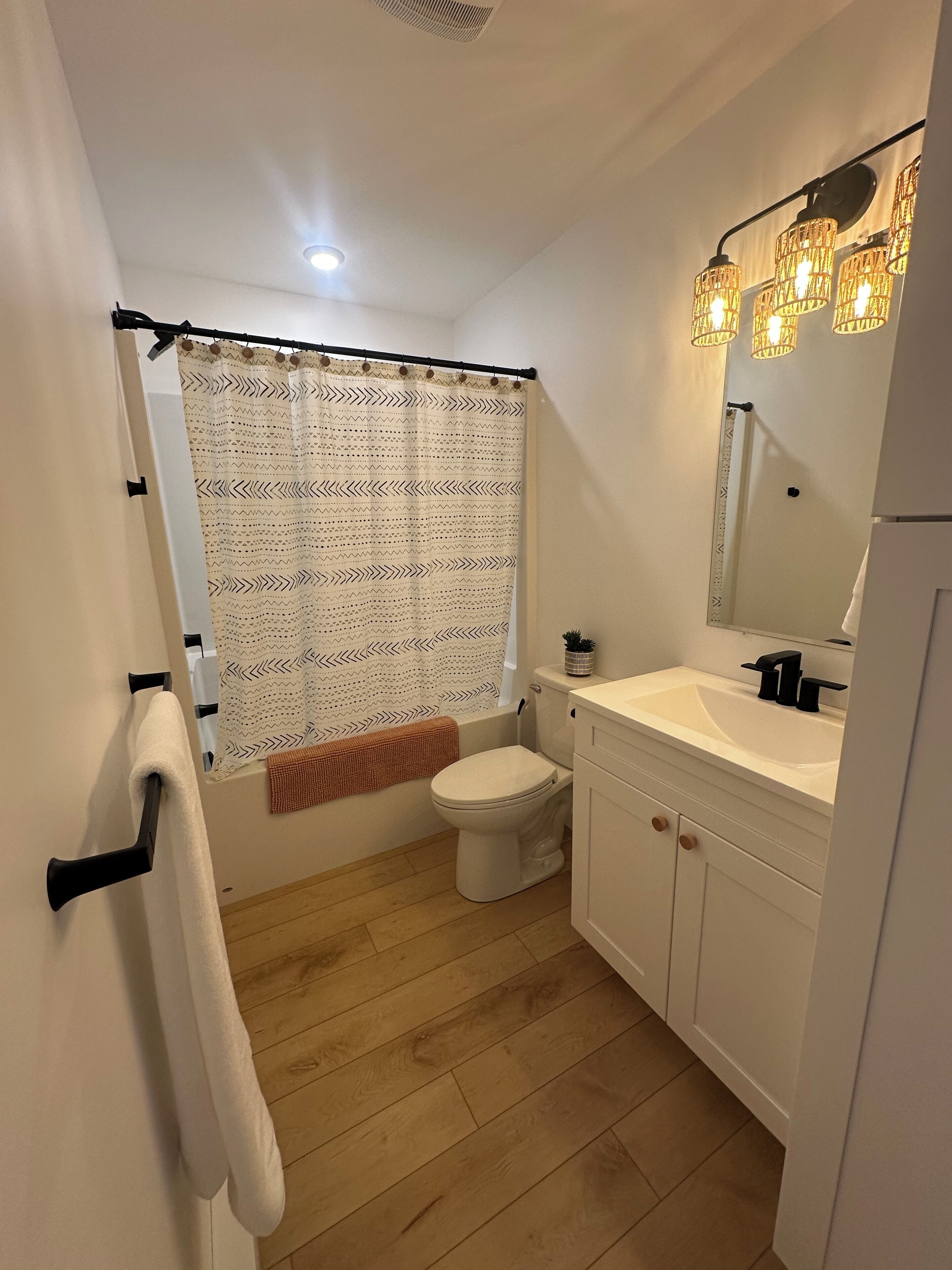 A bathroom with a toilet, sink, mirror, and shower curtain.