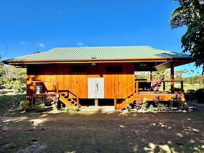 A wooden cabin with a porch, a staircase, and a small outdoor seating area.