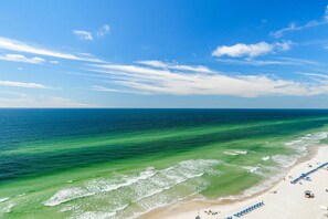 Uma praia com águas turquesa cristalinas, areal arenoso e alguns guarda-sóis.