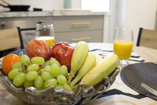 A fruit bowl with grapes, apples, and bananas on a table.