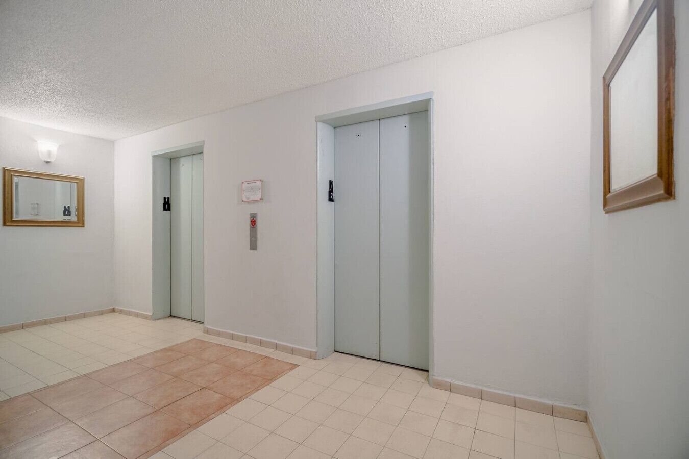 A hallway with two doors, a light switch, and a small sign on the wall.