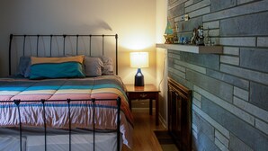 A bedroom with a bed, a nightstand, a lamp, and a fireplace. - Huge Manor w Indoor Hot Tub and Pool Table (Bloomington)