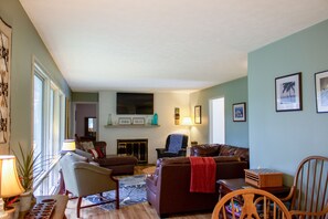 A living room with a fireplace, a sofa, a chair, and a table with a lamp. - Huge Manor w Indoor Hot Tub and Pool Table (Bloomington)