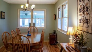 A dining room with a wooden table and chairs, a chandelier, and a window with a view. - Huge Manor w Indoor Hot Tub and Pool Table (Bloomington)