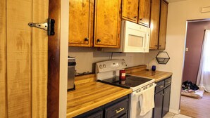 A kitchen with wooden cabinets, a microwave, an oven, and a dishwasher.